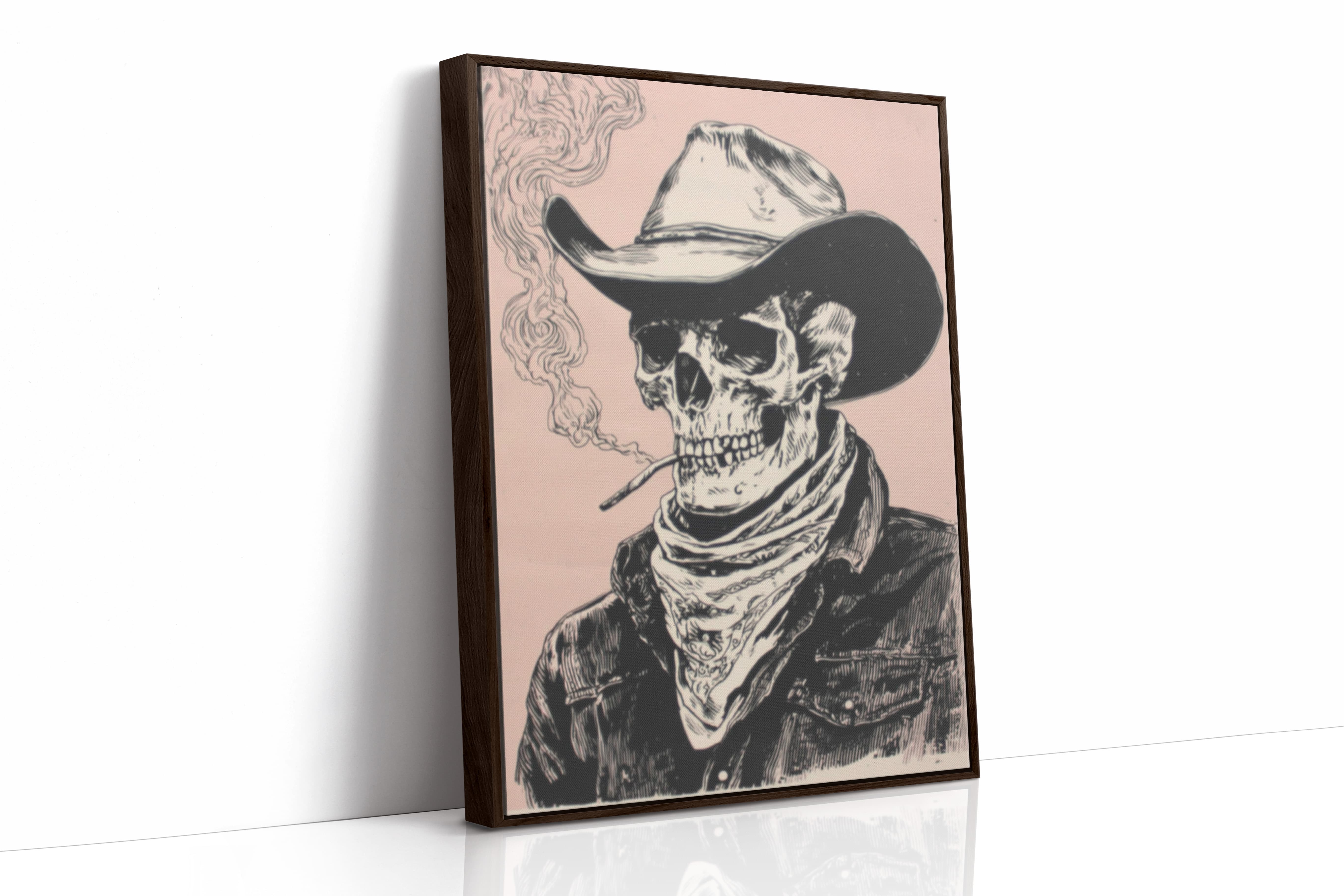 A framed art print featuring a black and white illustrated skeleton wearing a cowboy hat and bandana, smoking a cigarette against a pale pink background. The print is shown standing upright at a slight angle on a white surface with a clean white wall behind it.