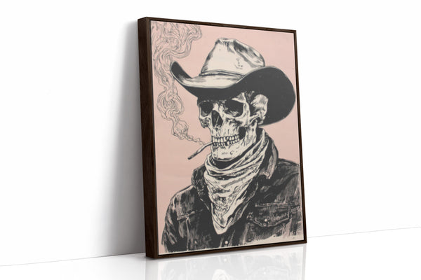 A framed art print featuring a black and white illustrated skeleton wearing a cowboy hat and bandana, smoking a cigarette against a pale pink background. The print is shown standing upright at a slight angle on a white surface with a clean white wall behind it.