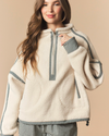 A woman wearing a cream sherpa fleece half-zip pullover sweatshirt with black and white gingham trim details, paired with matching gingham pants, against a solid beige background.