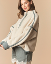 A woman wearing a cream-colored fuzzy quarter-zip pullover sweater with dark green and white gingham patterned stripes, paired with a matching gingham mini skirt, set against a solid beige background.