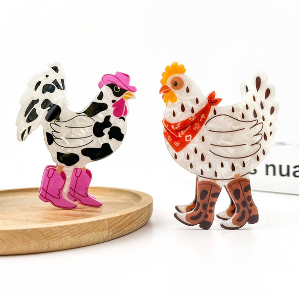 Two decorative chicken claw clips with western boots and accessories, displayed on a light wood tray against a white background.