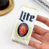 Hand holding a Miller Lite beer can claw clip against a white background