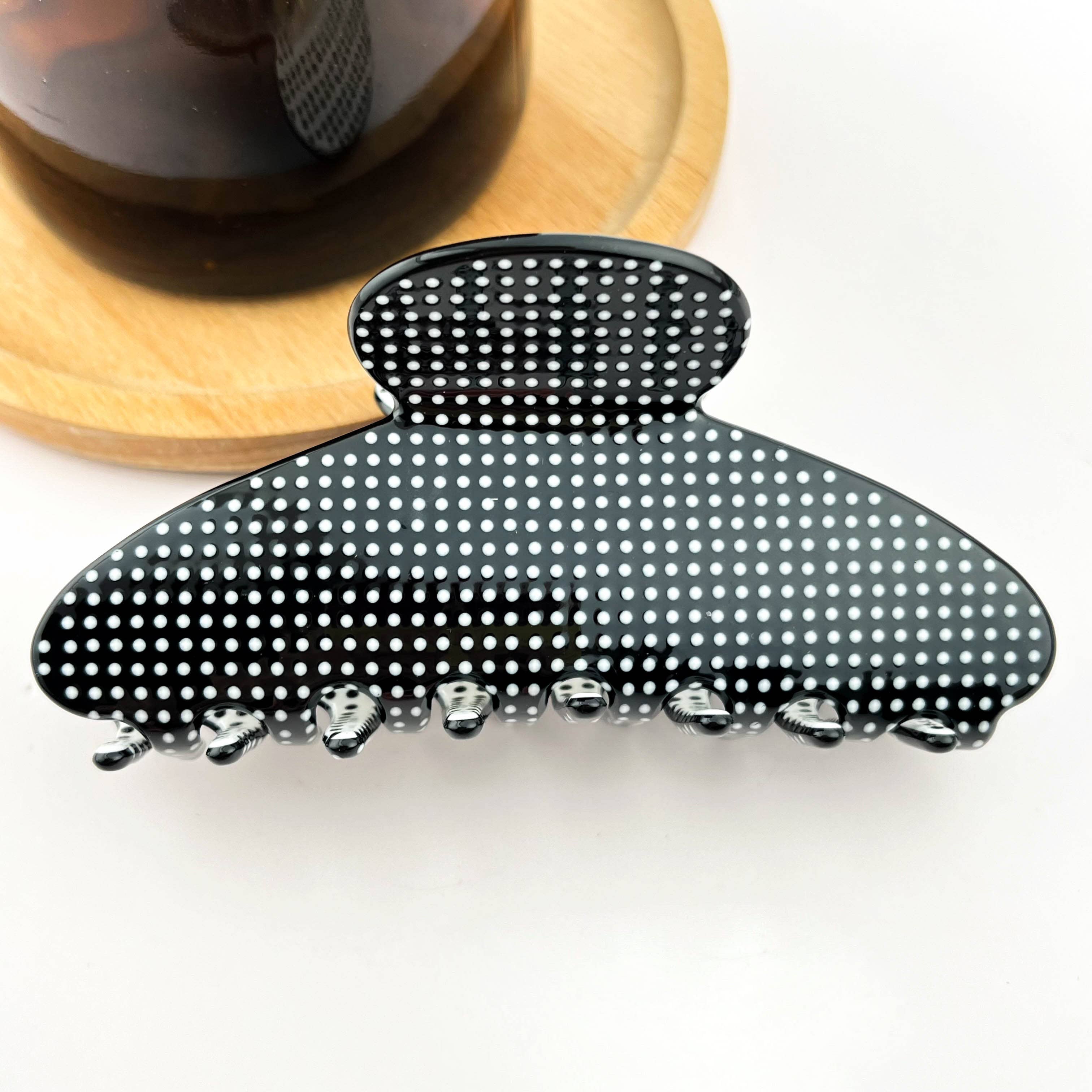 Black hair claw clip with white polka dots on a white background