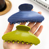 Hand holding two polka dot hair clips, one blue and one green, on a white background.