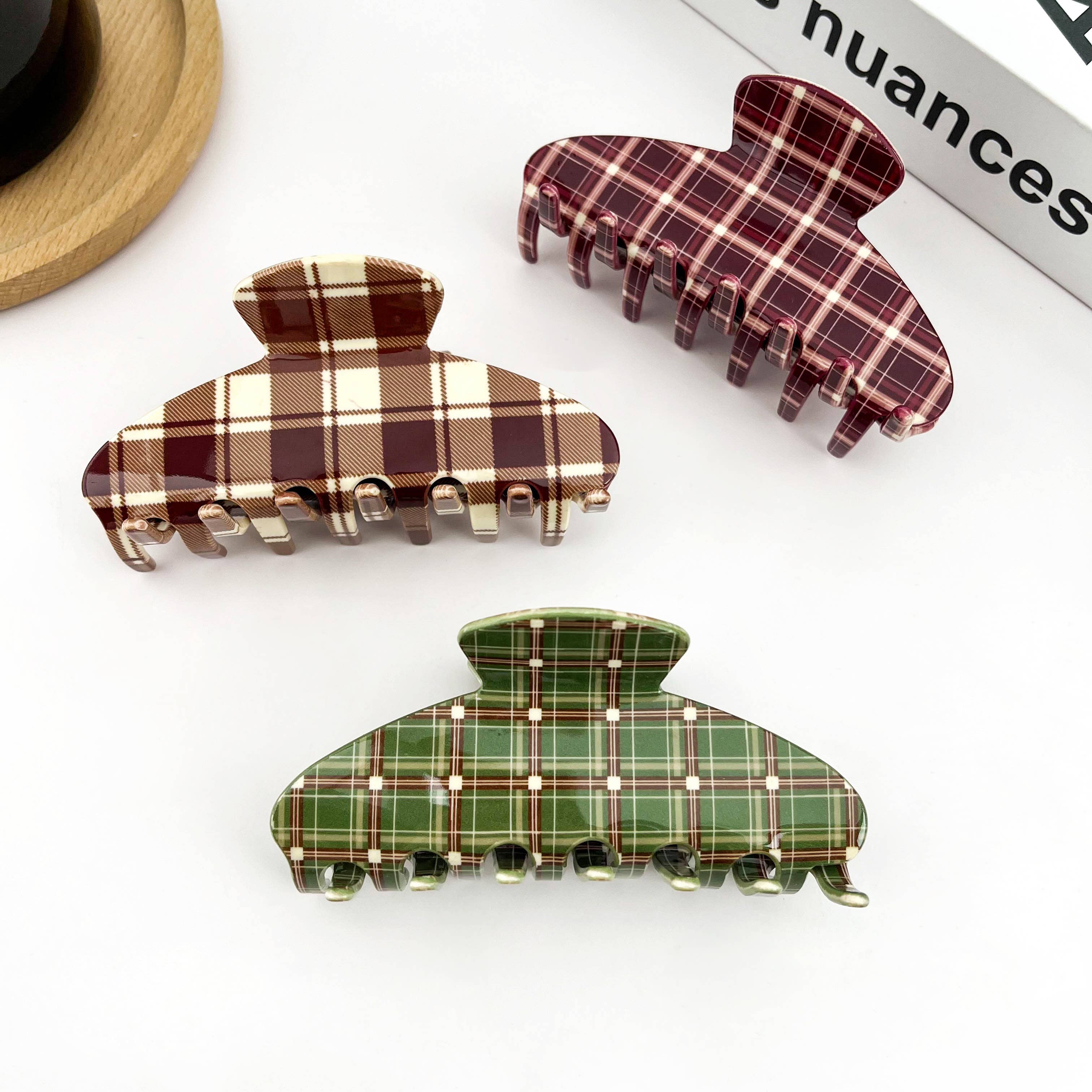 Three plaid hair clips in brown, red, and green on a white background.