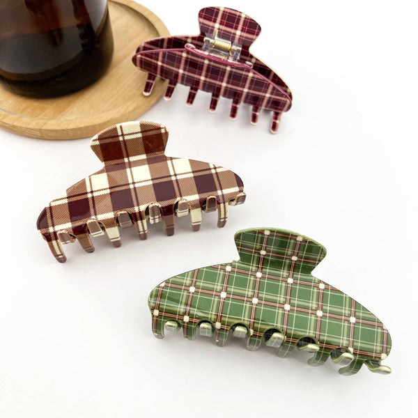 Three plaid hair clips in brown, green, and red on a white background.