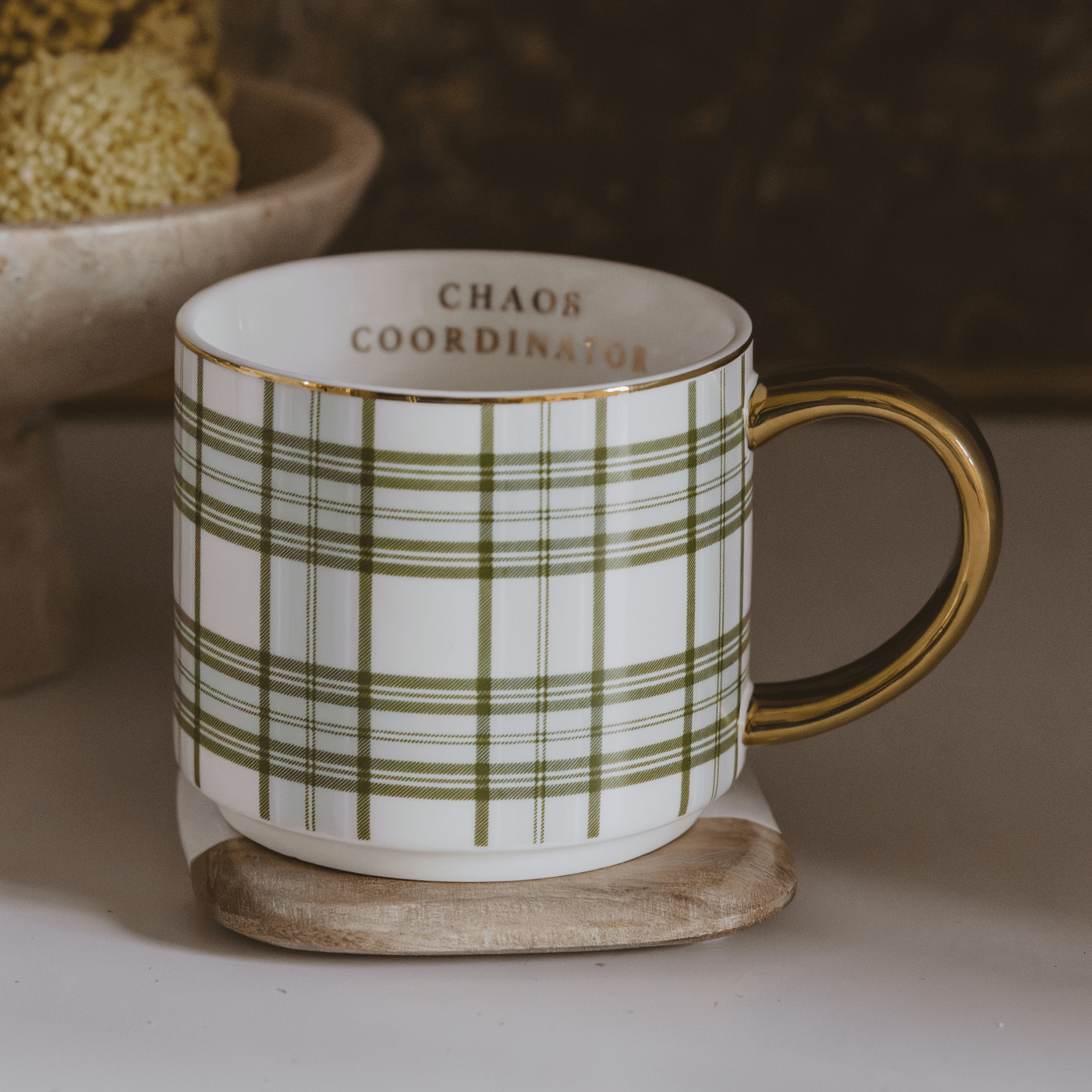 Mug with green plaid pattern and 'Chaos Coordinator' text on a coaster.