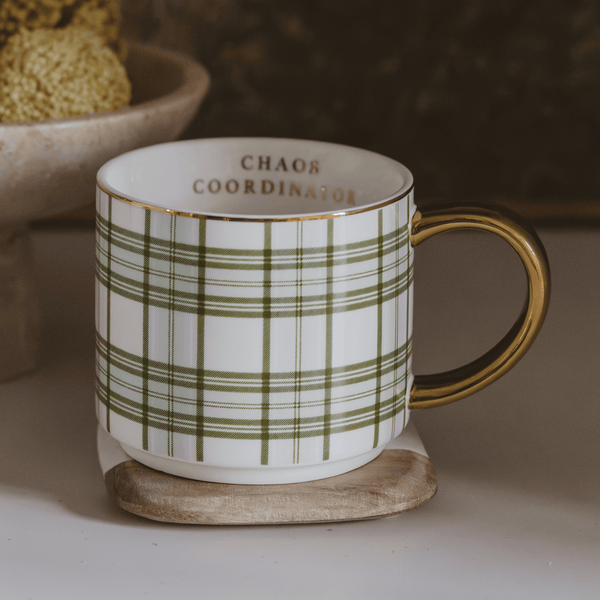 Mug with green plaid pattern and 'Chaos Coordinator' text on a coaster.